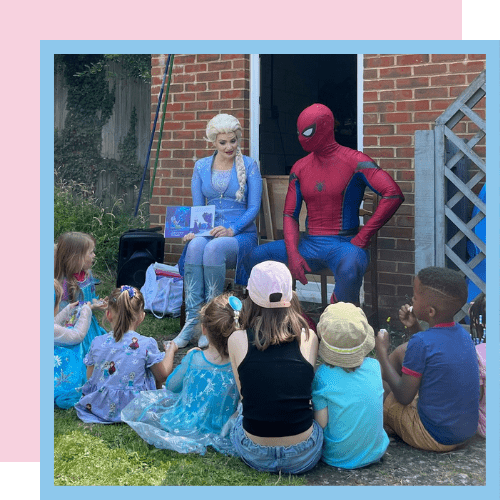 Elsa and Spider-Man reading a story to a group of children in a garden